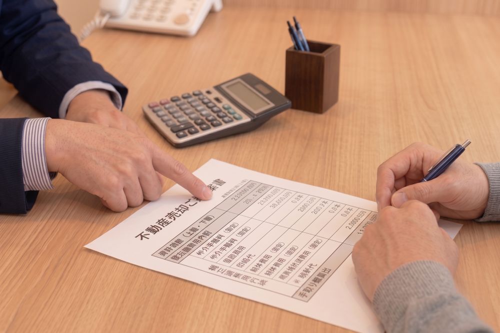 売却ご提案書を指し示して売却の流れを説明する手元